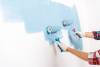 cropped view of man and woman painting wall in blue color at home